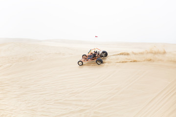 A sand rail speeding along the ridge of a sand dune