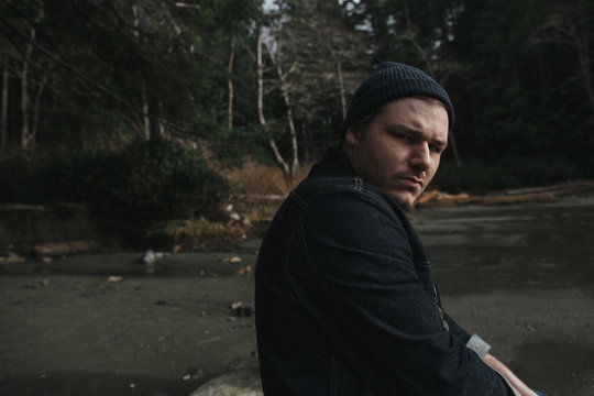 Mid 30's man looking grimly at camera on beach