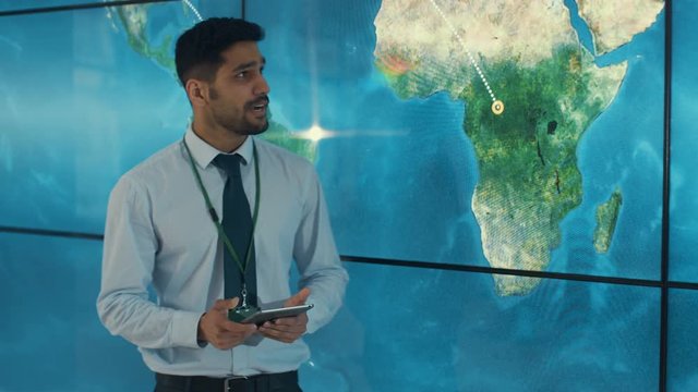  Businessman with tablet giving a presentation in front of large world map