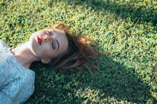Young woman with eyes closed laying on grass
