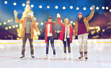 happy friends waving hands on outdoor skating rink