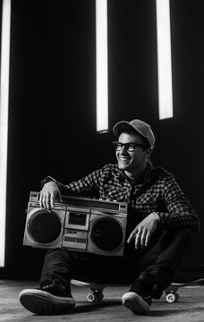 Young urban man smiling and listinig music from boom box/ghetto blaster.