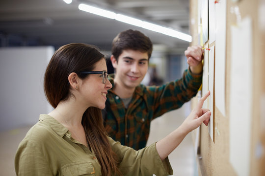 Young couple of students looking at the grades of the university board