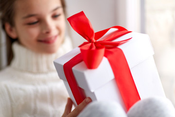 girl with christmas gift sitting on sill at home