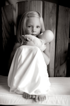 Little Girl In White Slip Dress Holding Baby Doll