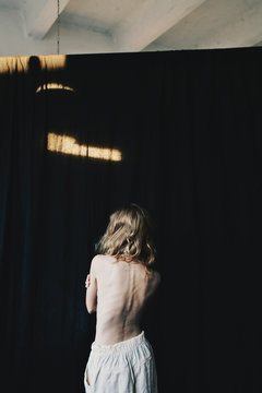 Back view of a young thin blonde woman with long hair