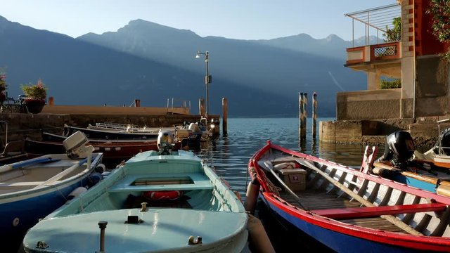 Boats sway on the waves at the pier in Limone sul Garda on a sunny morning.