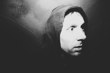 Portrait of man with surprised and disturbed face, hiding in urban tunnel