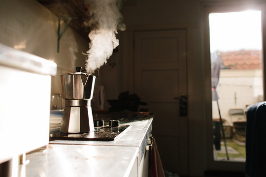 Coffee maker blowing seem on a stove in the morning sunlight