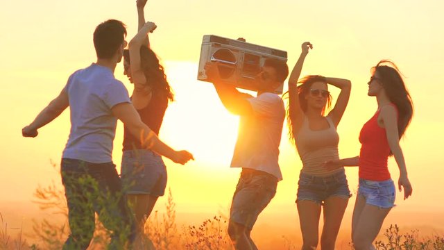 The happy people with a boom box dancing on a dawn background. slow motion