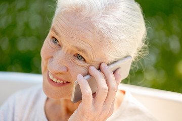 happy senior woman calling on smartphone in summer