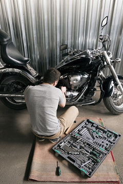 Back view of man reparing motorcycle