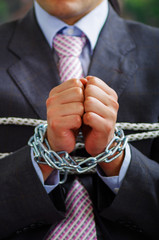Close up of a businessman with chains in his hands, in a blurred background