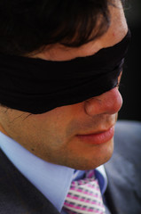 Portrait of a businessman, with a black tape in his eyes in a blurred background