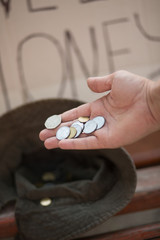 Close up view of hand with coins. Man giving alms to homeless person, putting coins into a hat.
