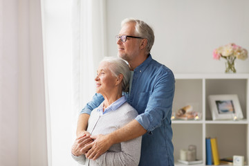 happy senior couple looking through window at home