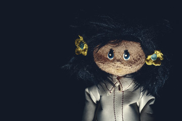 Sinister vintage rag doll with long dark hair and white leather coat. On black