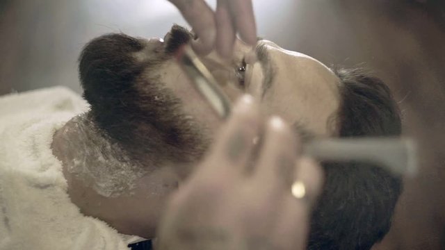 Beard cut with straight razor shave. Close up of shaving beard in barber shop. Male beard style. Man beard shave process. Barber shaving man. Barber shave