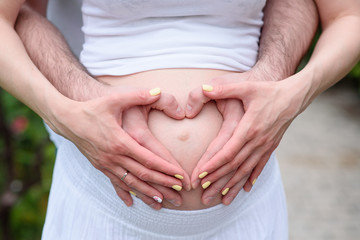 Hands on the stomach of a pregnant girl.