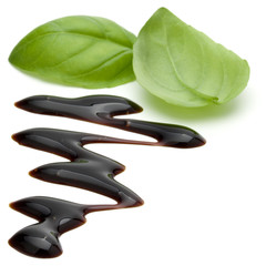 Obraz premium Balsamic vinegar cream and basil leaves isolated on white background. Italian salad dressing, sauce.