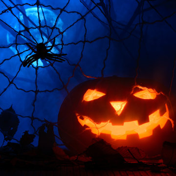 Horrible Halloween pumpkin in the background of the web and the full moon in the fog