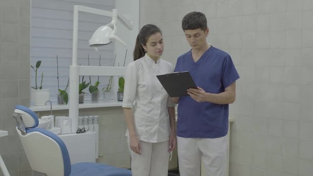 A young attractive male and female doctors checks patient's medical card.