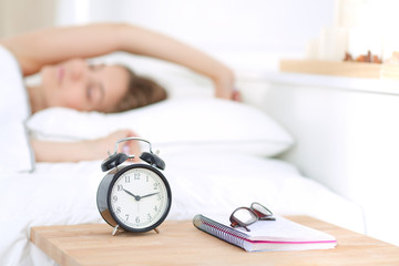 A young woman putting her alarm clock off in the morning.