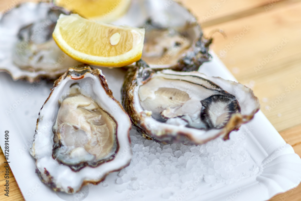 Wall mural Tasty fresh oysters with sliced juicy lemon on plate. Aphrodisia