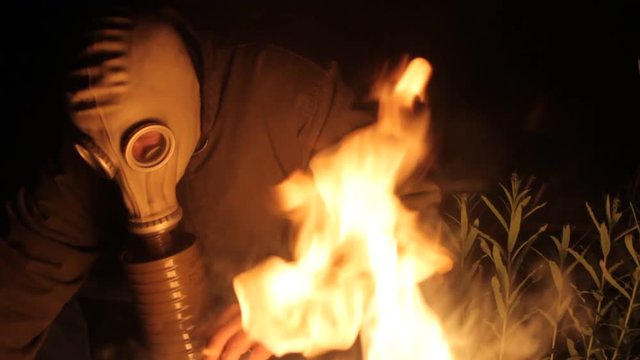 person in a gas mask is heated by the fire