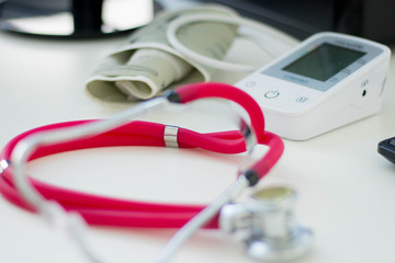  a red stethoscope and a pressure measuring instrument located on a doctor's closeup