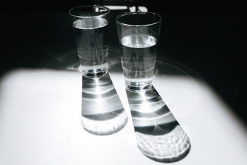Close up photo of two glasses of water on office table. Beautiful photo of glasses with clear water standing on table with shadows