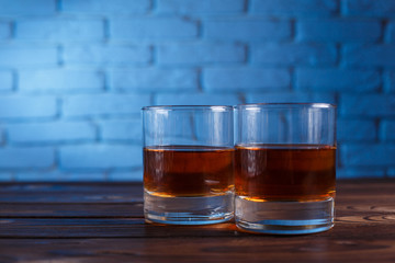 Two glasses of whiskey with ice cubes on wooden table, copy space.  Alcohol drinks, bar concept