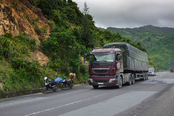 Fototapeta na wymiar Vietnam Pass, a mountain pass, a truck drives two motorcycles traveling along a serpentine road.