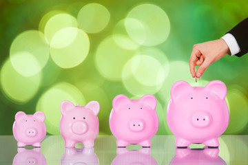 Businessman Inserting Coin In Piggybank At Office Desk