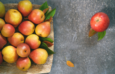 Juicy pears on the plate with gray bachground and apple on the side