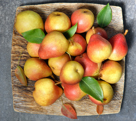 Juicy pears with leaves on the wooden plate