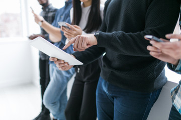 Young men and women holding cell phones and a tablet