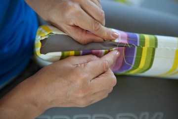 A woman sews a bright cloth with a needle. Manual sewing. Needlework.