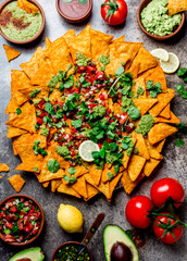 Nachos. Totopos with sauces. Mexican food concept. Yellow corn totopos chips with different sauces salsas - pico del gallo, guacamole, salsa verde, chili pebre and fresh avocado, tomatoes, lemon and