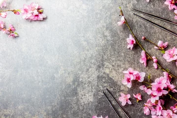 Fotobehang Chopsticks and sakura branches on gray stone background. Japanese food concept. Top view, copy space. © lblinova