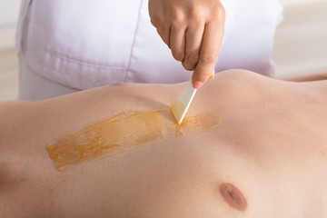 Beautician Applying Wax On Man's Chest