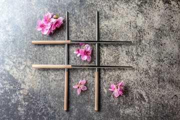 Fototapeta na wymiar Chopsticks and sakura flowers on gray stone background. Japanese food concept. Top view, copy space