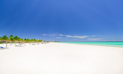 gorgeous beautiful white sand tropical palm beach and tranquil turquoise ocean view with people in background at Cuban Cayo Coco island on sunny nice day