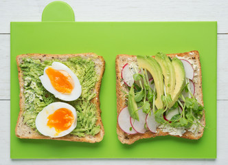 Two avocado toasts on green