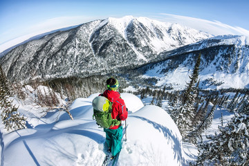 Man standing at top of ridge. Ski touring in mountains. Adventure winter freeride extreme sport