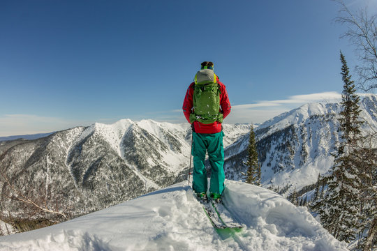 Man standing at top of ridge. Ski touring in mountains. Adventure winter freeride extreme sport