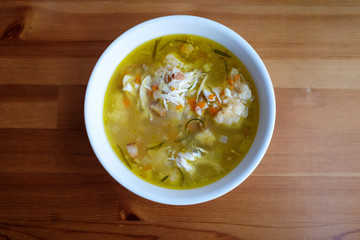 Homemade chicken and dumpling soup on a wooden table.