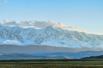 Fototapeta premium panoramic view of plain at root of great mountains with snowy tops 