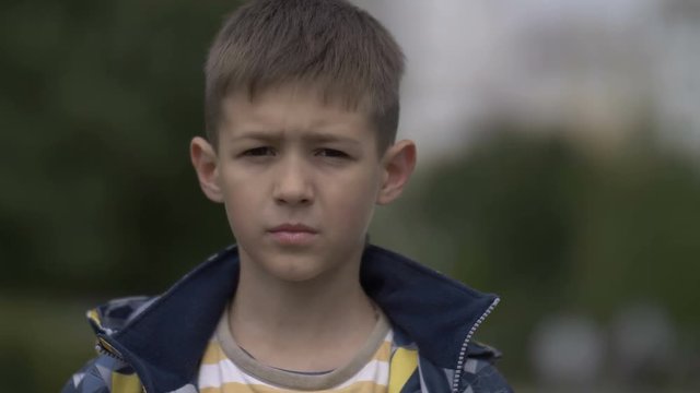 portrait of a serious boy with a tence glance looking at the camera, close-up heavy face