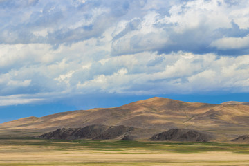 huge grey fluffy clouds over great mountains at sunset
